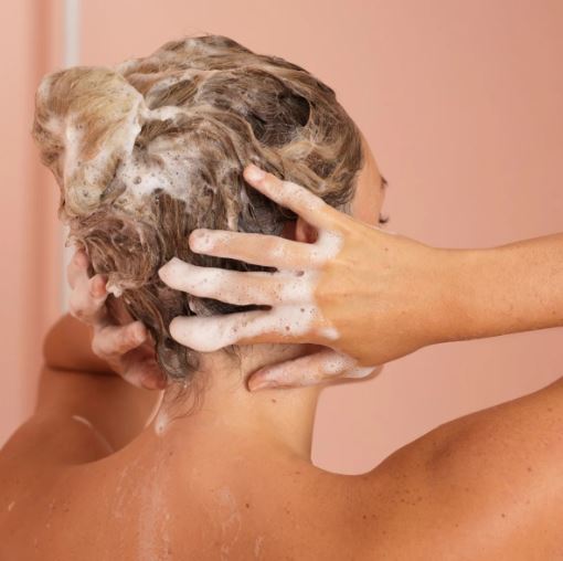 Woman washes her hair with the ReNu Volumizing Shampoo from Nu Skin